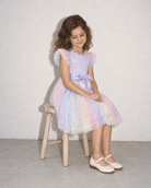 Girl sitting in a purple tulle dress, showing the soft layered skirt, comfortable fit and pastel party dress style for special occasions.