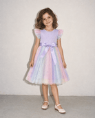 Girl wearing a purple tulle party dress in a front standing pose, showing the pastel layered skirt, fitted bodice and flutter sleeve design.