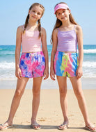 Girls wearing colorful tie dye shorts at the beach, stylish summer vacation outfit perfect for seaside activities and holidays.