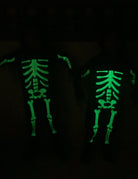 Kids skeleton costume glowing in the dark with bright bone graphics after absorbing light, showing the Halloween costume glow effect.