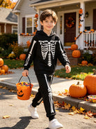 Child wearing a black glow skeleton hoodie and pants costume outdoors during Halloween season, showing the full two piece costume look.