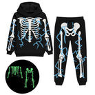 Kids black skeleton costume set showing the hooded pullover top and matching long pants with glow in the dark bone graphics.