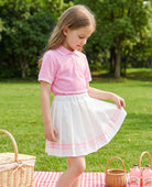 little girl wearing pink tennis polo dress set outdoors with pleated skirt summer outfit
