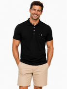 Man wearing a black performance polo shirt with stretch fabric, classic collar and comfortable fit for golf and everyday wear.