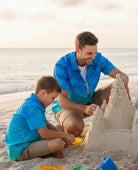 Man wearing a lightweight tropical shirt while spending time on the beach with family.
