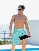 Man wearing blue flamingo swim trunks while stretching the black compression liner to demonstrate its flexible supportive design.