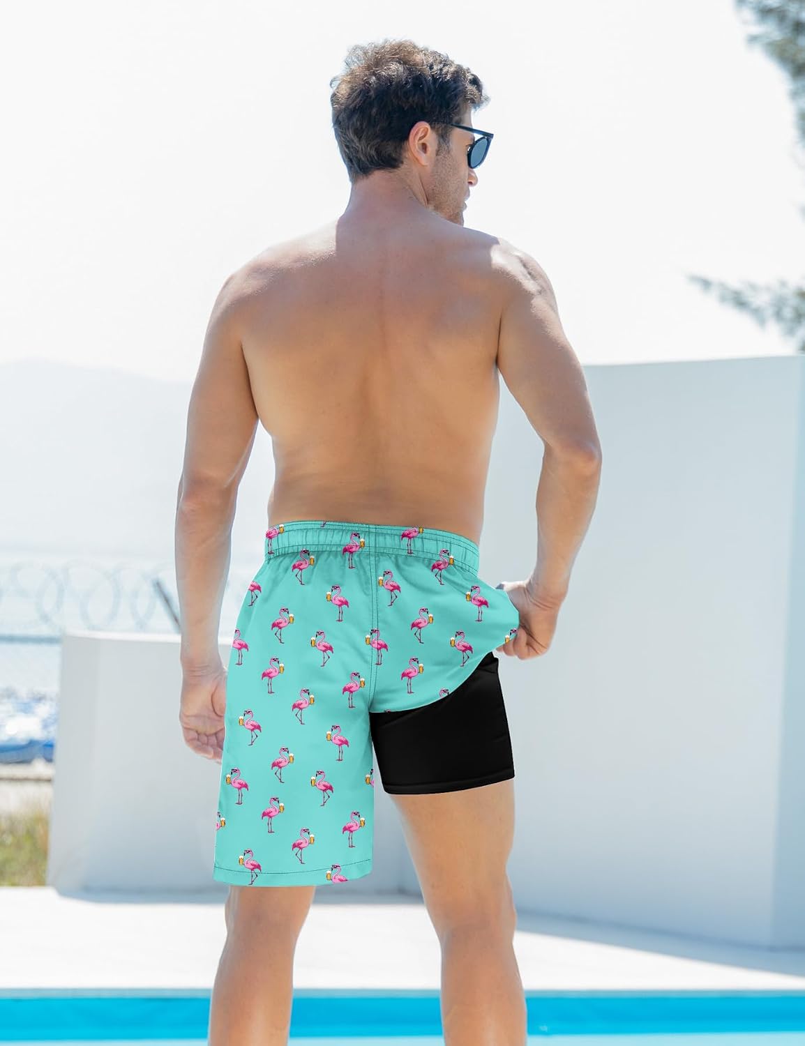 Back view of blue flamingo 2-in-1 swim trunks with the outer layer lifted to show the built-in black compression liner.