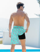 Back view of blue flamingo 2-in-1 swim trunks with the outer layer lifted to show the built-in black compression liner.