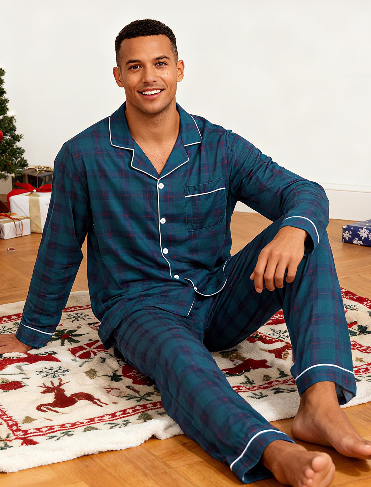 Man wearing navy plaid pajamas preparing Christmas gifts beside a decorated Christmas tree