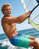 Man wearing blue palm tree swim trunks while enjoying a sailing vacation