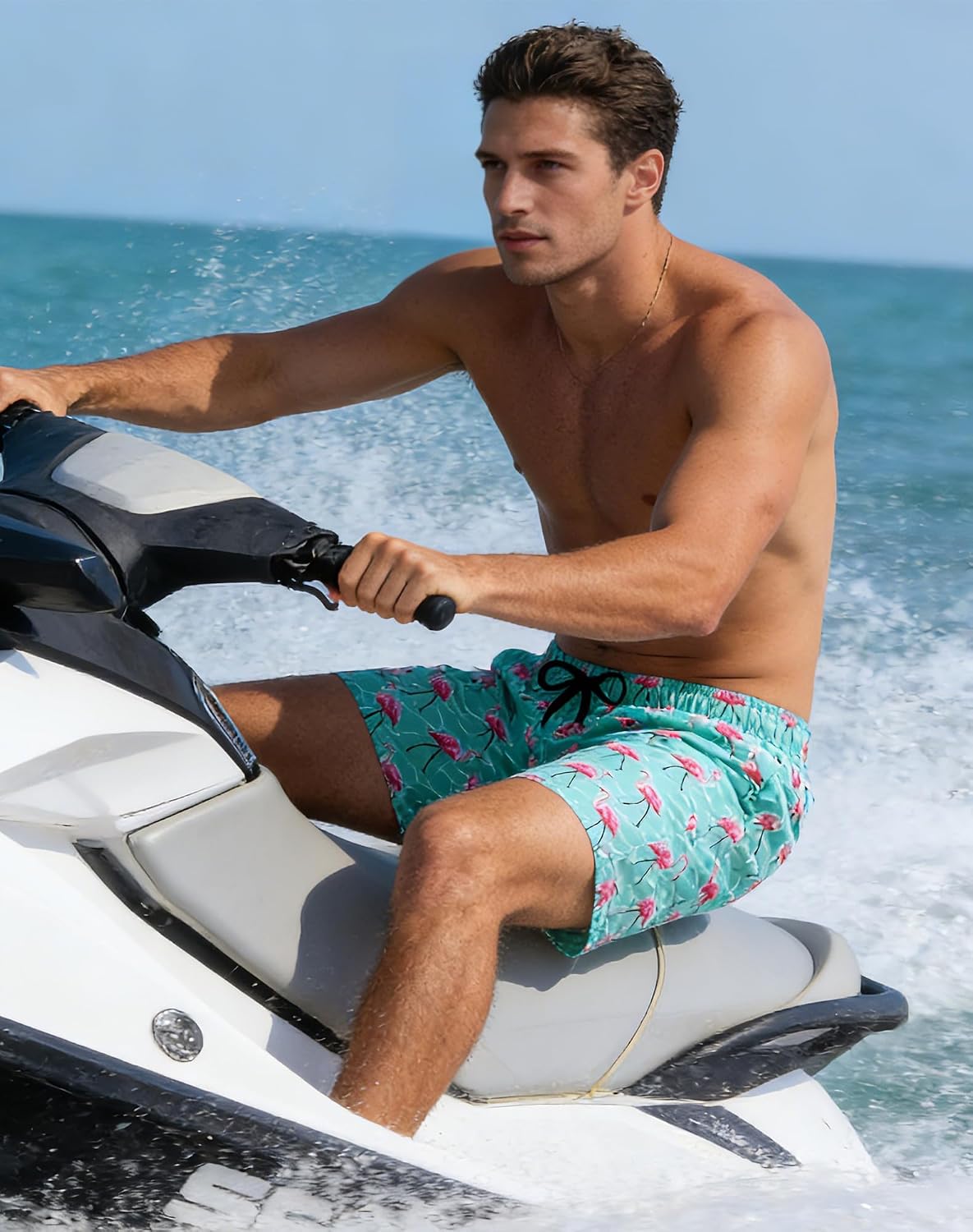 Man wearing green flamingo swim trunks while riding a jet ski, styled for beach vacations and active water activities.