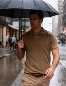 Man wearing a khaki textured knit polo shirt in a casual outdoor setting, styled as a comfortable everyday summer outfit.