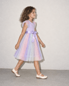 Girl walking in a purple tulle party dress, showing the flowing layered skirt, side silhouette and lightweight movement of the dress.