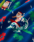Close-up of Santa's Vacation pajama pants showing the colorful Santa, tropical and holiday graphics printed on blue polyester fabric.