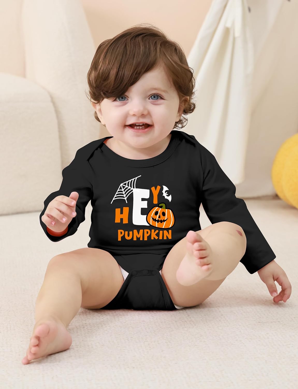 Toddler wearing a black Halloween graphic long sleeve bodysuit while sitting indoors, showing the comfortable fit for fall and holiday wear.