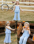 Toddler girl wearing a light blue cotton two piece outfit with ruffle top and wide leg pants in an outdoor setting.