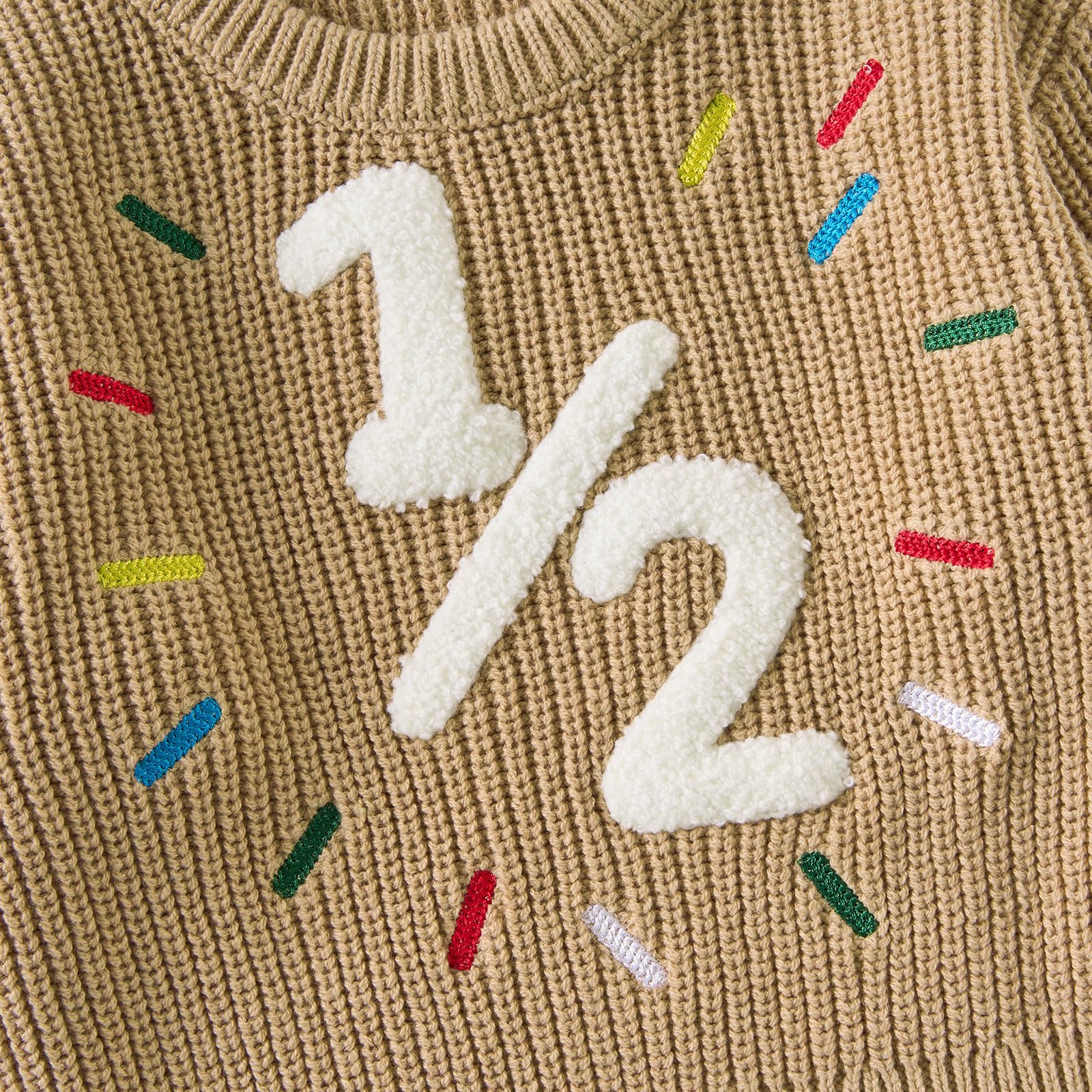 Close-up of the raised white 1/2 birthday design with colorful embroidered sprinkle details on a khaki toddler knit sweater.