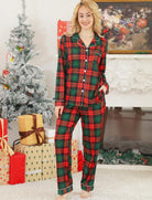Woman wearing classic green and red plaid pajama set with Christmas decorations and presents